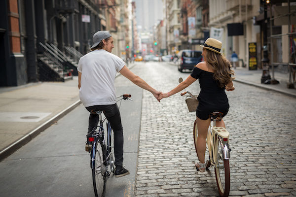 Lovers riding bicycle together holding hands