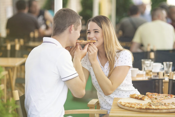 couple sharing a slice of pizza at a restaurant