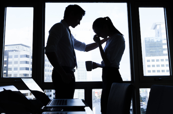 man consoling upset woman in an office