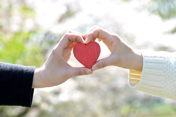 man and woman hands holding a red heart