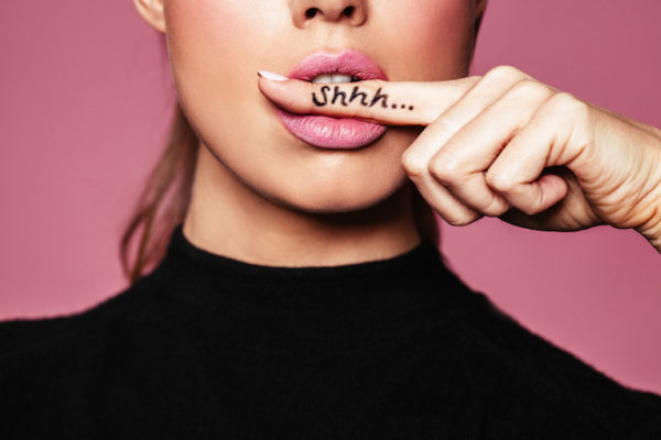 woman with pink lipstick biting her finger that says shhh