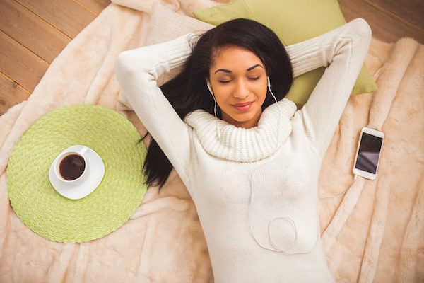 girl laying on a blanket with coffee and headphones in her ears